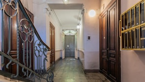 Un couloir avec un escalier, des portes en bois et un sol carrelé.