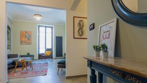 Un salon avec un canapé, une table basse et un fauteuil. Il y a une fenêtre qui donne sur l’extérieur.