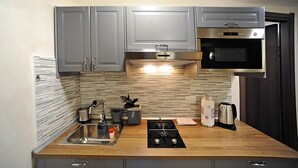 A modern kitchen with grey cabinets, a stainless steel oven, a microwave, and a wooden countertop.