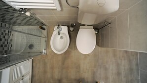 A modern bathroom with a shower, two sinks, and a toilet.