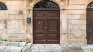A double wooden door with a metal arch above it, set in a stone building.