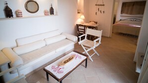A cozy living room with a white sofa, a wooden coffee table, and a dining area with a table and chairs. - Relais Patriarca - Tirrenia - Utnz - IBR CAV (Ostuni)