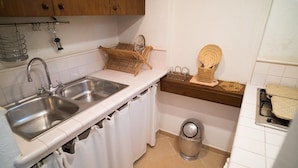 A kitchen with two sinks, a wooden rack, a waste bin, and a small shelf with baskets. - Relais Patriarca - Tirrenia - Utnz - IBR CAV (Ostuni)
