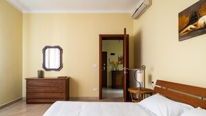 A bedroom with a bed, dresser, mirror, and a painting on the wall.
