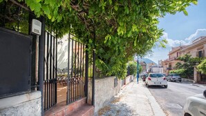 Straßenansicht mit parkenden Autos, Bürgersteig und Gebäuden mit Balkonen.