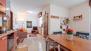 A modern kitchen with a dining area, a sofa, and a TV.