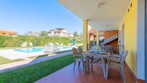 A patio with a pool, outdoor furniture, and a view of the neighborhood.