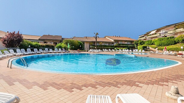 A swimming pool with sun loungers and a tiled deck. - Kristall Lago 233 Apartment by Wonderful Italy (Desenzano del Garda)
