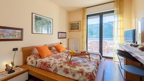 A bedroom with a bed, a desk, and a view of the outdoors. - Kristall Lago 233 Apartment by Wonderful Italy (Desenzano del Garda)
