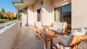A balcony with wicker furniture, a table, and a potted plant. - Kristall Lago 233 Apartment by Wonderful Italy (Desenzano del Garda)