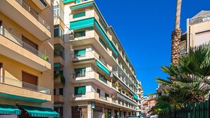 A multi-story building with balconies, a ground-level shop, and a palm tree. - I Fiori 3 16 Apartment by Wonderful Italy (Sanremo)