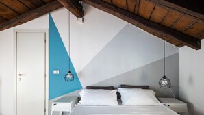 A bedroom with a sloped ceiling, a bed with white bedding, a white door, and a blue accent wall.