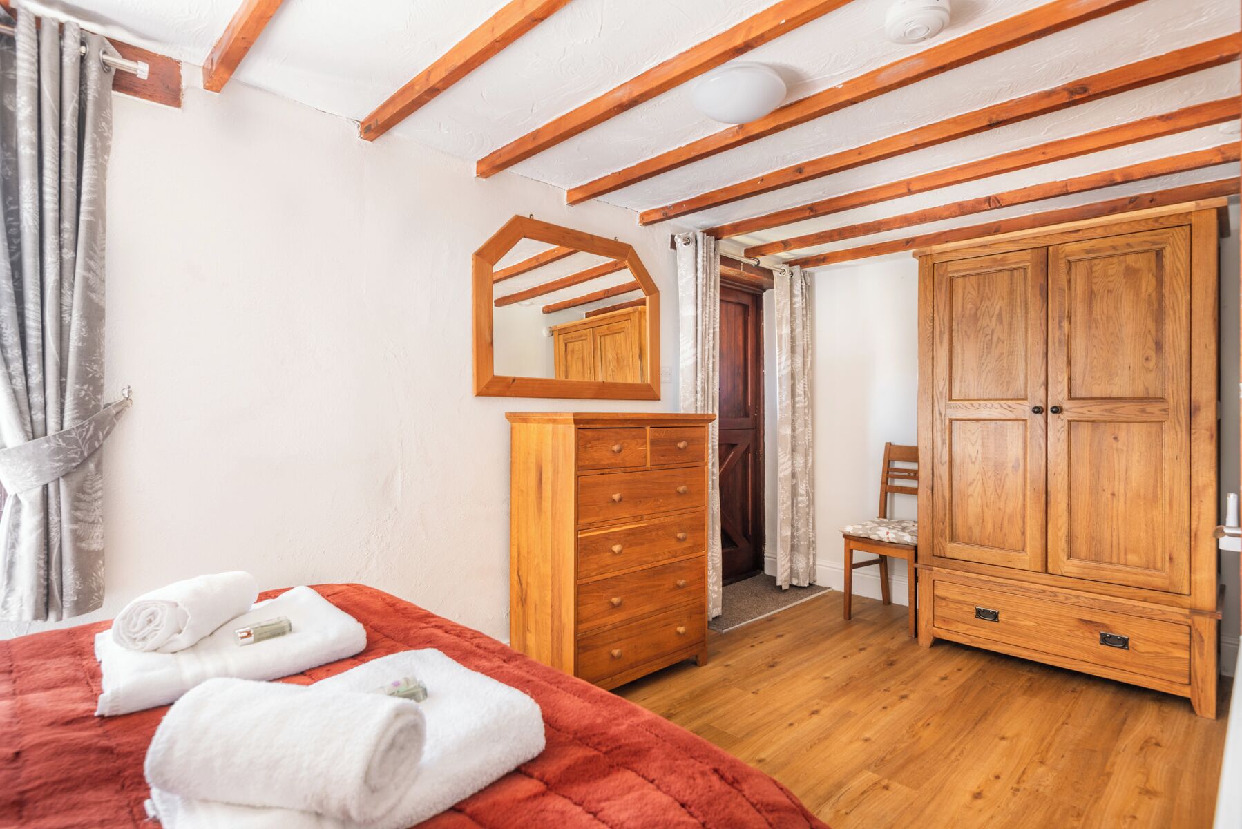 A bedroom with a bed, wooden wardrobe, and a mirror.