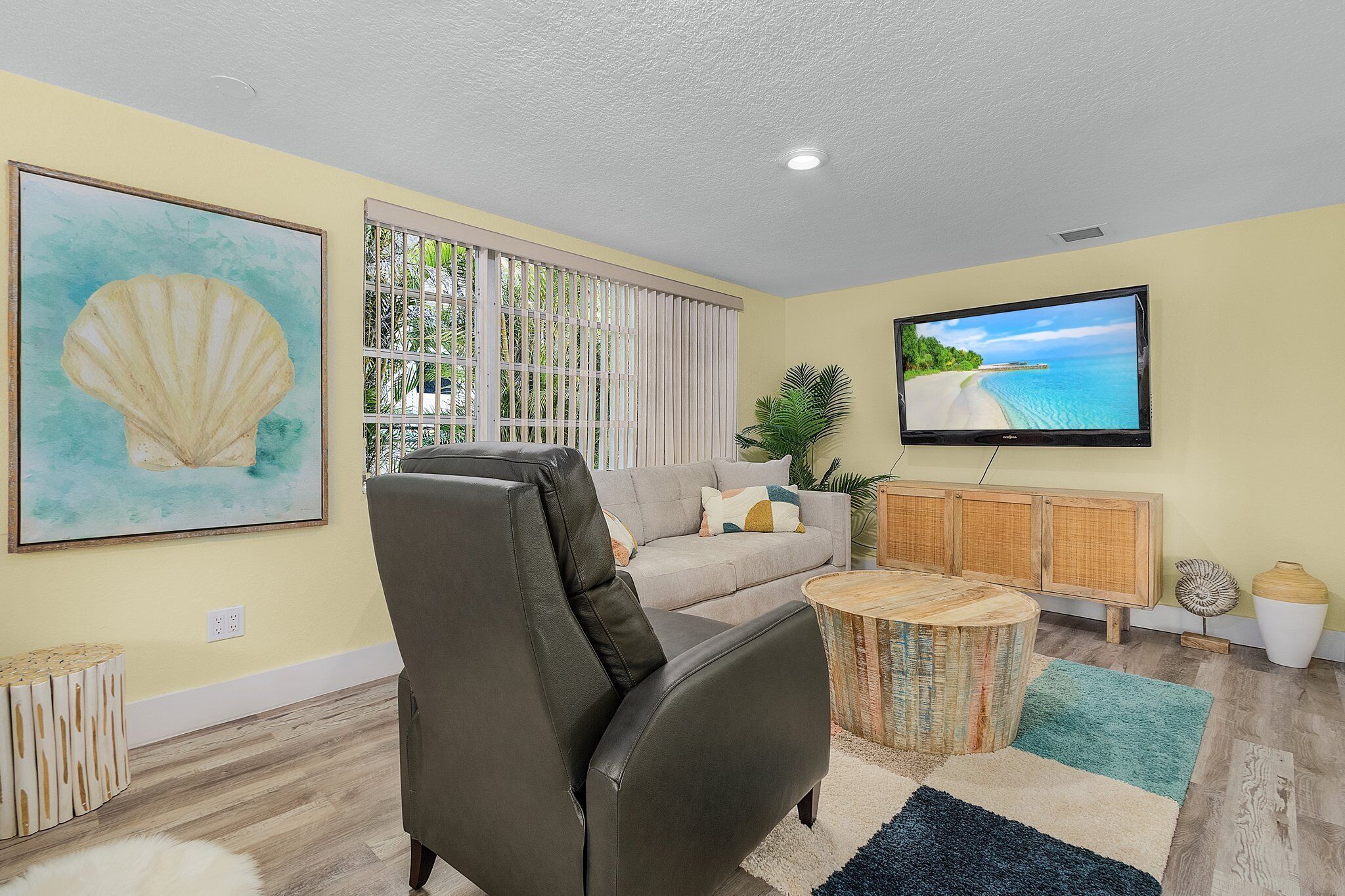A living room with a leather sofa, a television, a large painting, and a wooden cabinet.