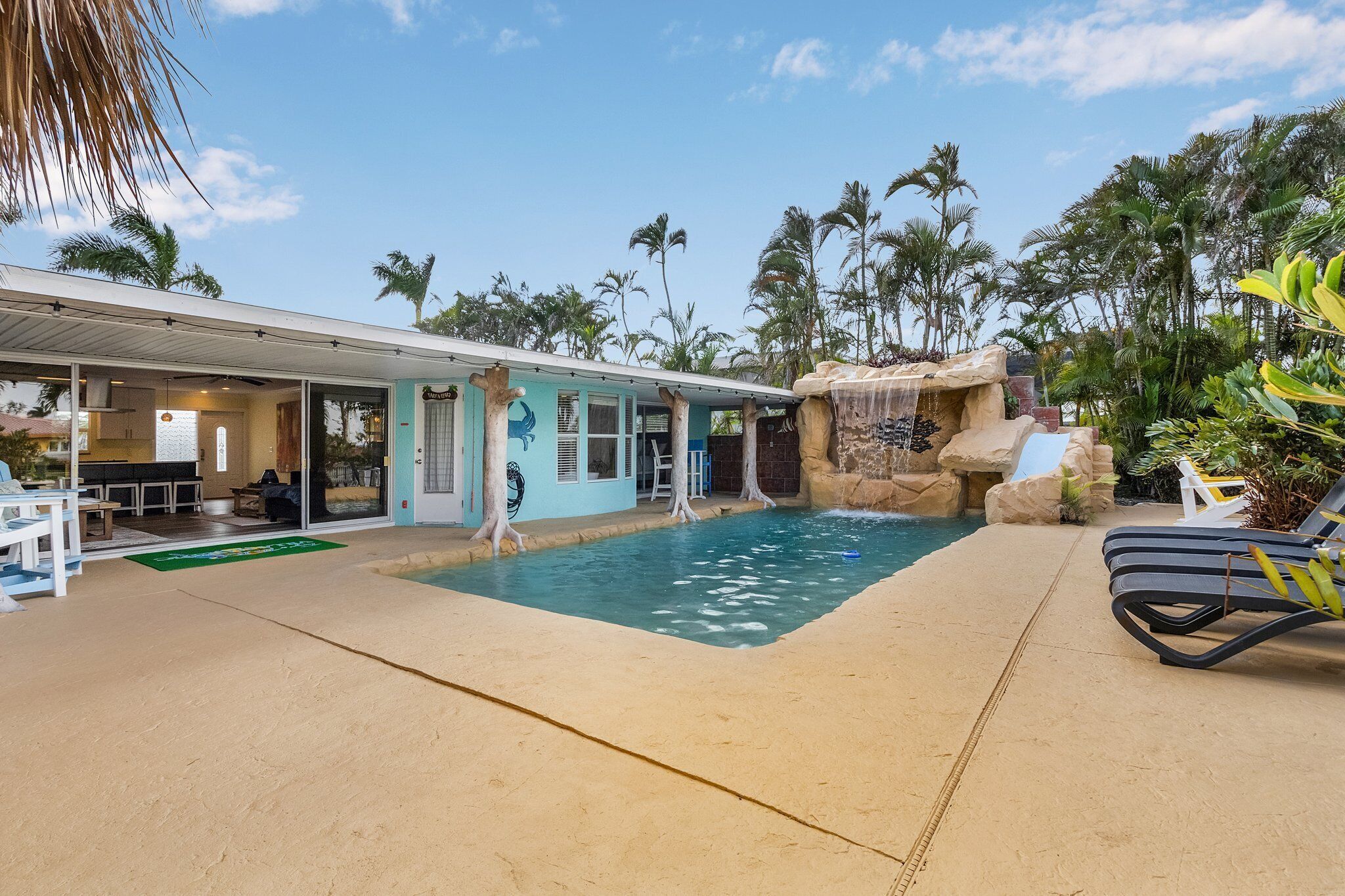 A pool area with a waterfall feature, lounge chairs, and a covered seating area.