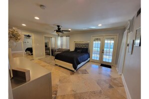 Spacious bedroom with a large bed, ceiling fan, and recessed lighting.
