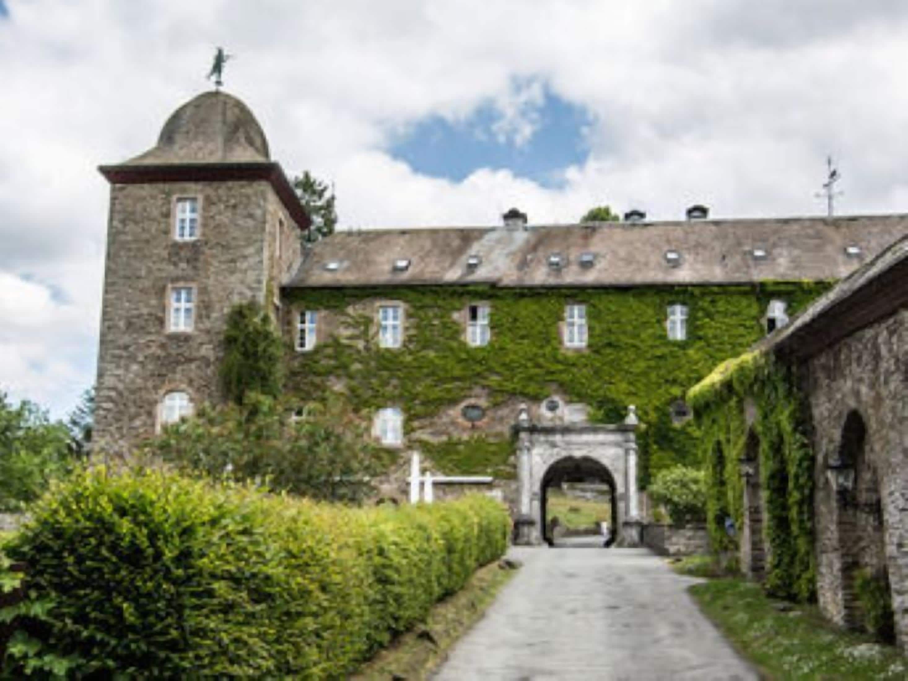 Un edificio histórico con una torre, un arco y un sendero que lleva a la entrada.