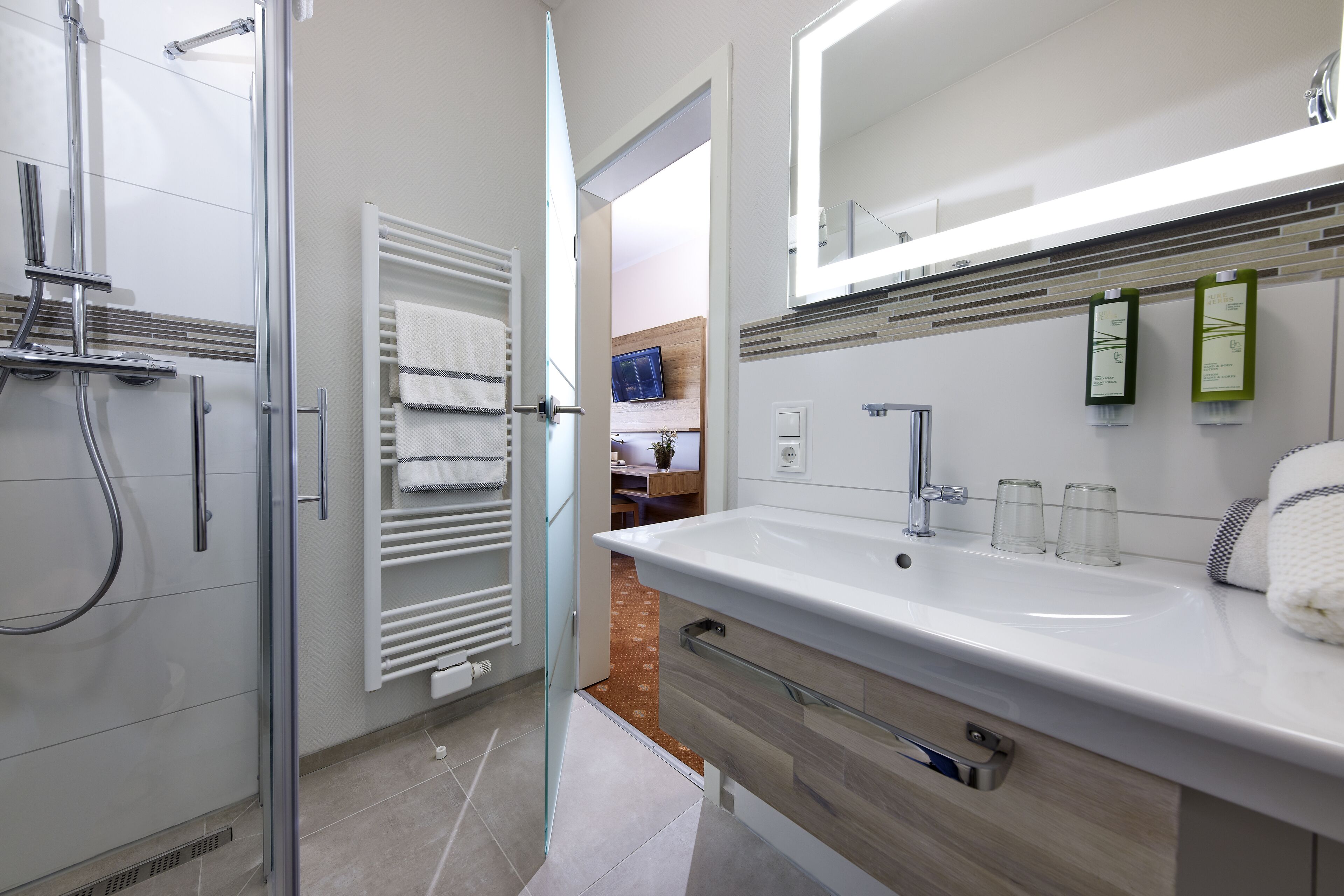 Ein modernes Badezimmer mit Dusche, Waschbecken und Spiegel.