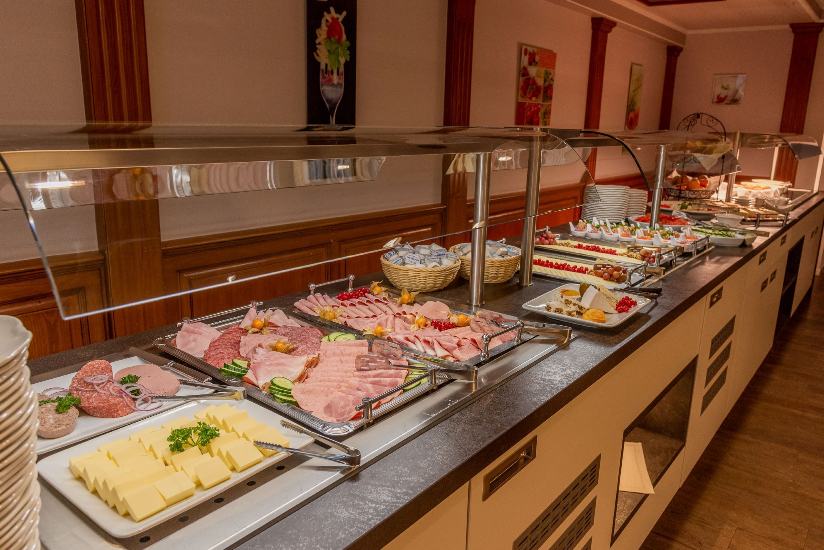 Un bufé con diversas opciones de comida, incluyendo carnes, quesos y frutas.