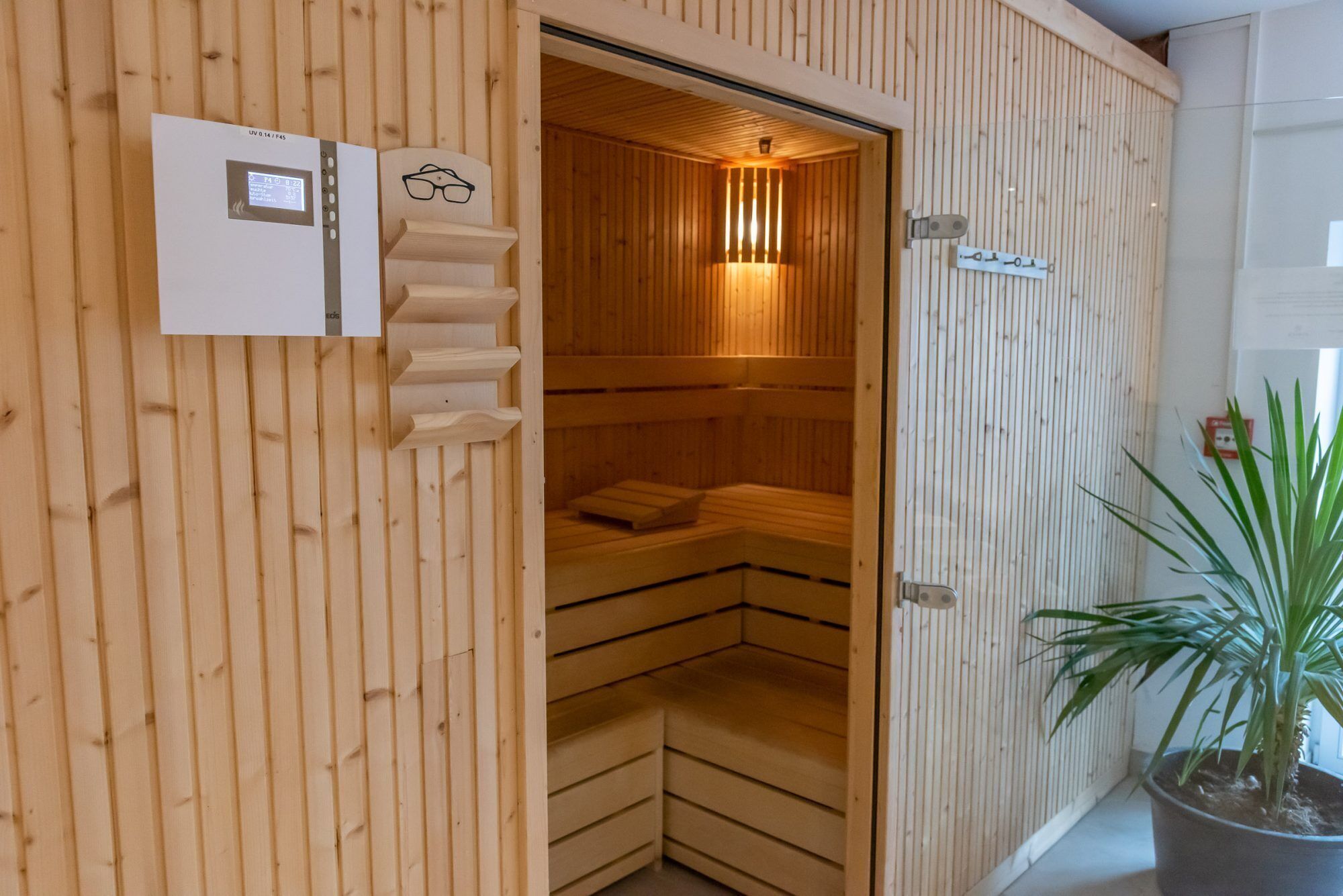 A sauna with wooden walls and benches, a control panel, and a sign indicating the temperature.