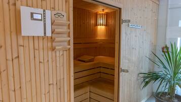 A sauna with wooden walls and benches, a control panel, and a sign indicating the temperature.
