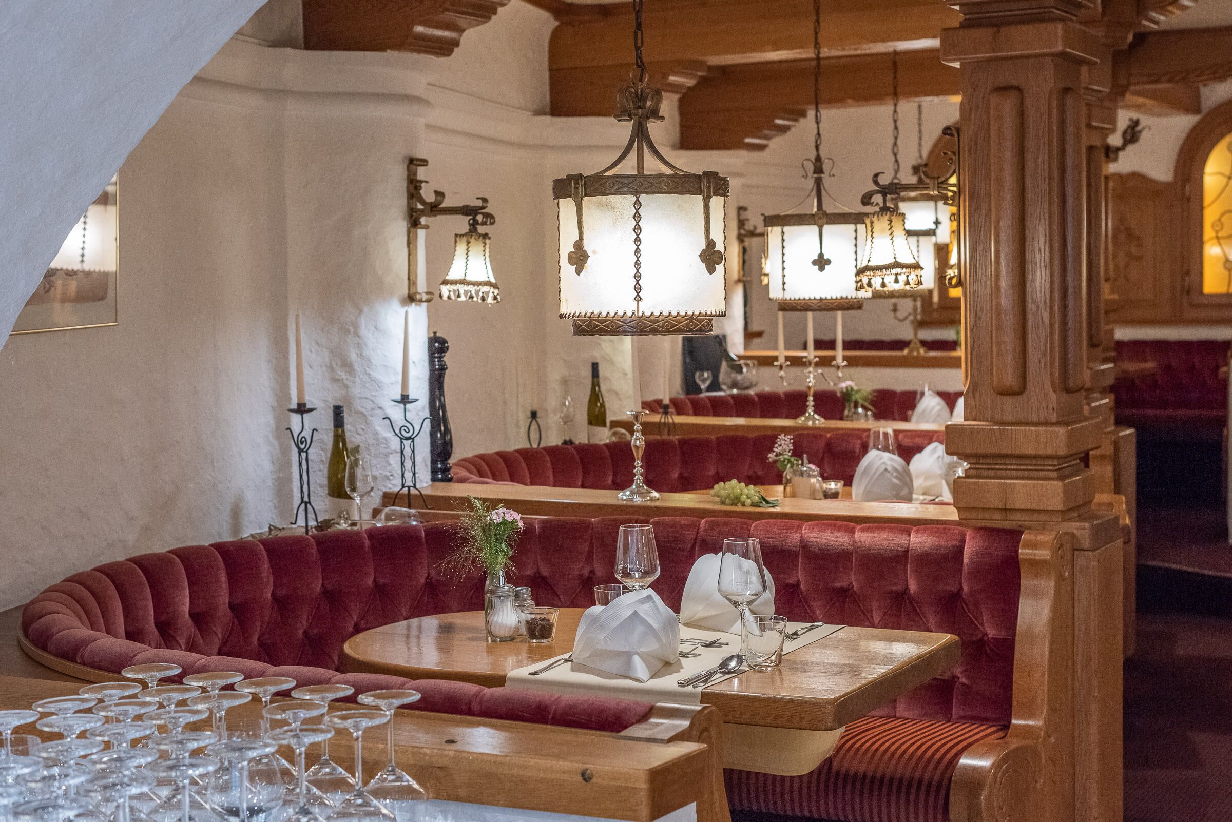 Un restaurante con asientos tapizados en rojo, mesas de madera y lámparas colgantes.