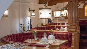 Un restaurante con asientos tapizados en rojo, mesas de madera y lámparas colgantes.