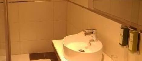 A modern bathroom with two sinks, a shower, and a large mirror.