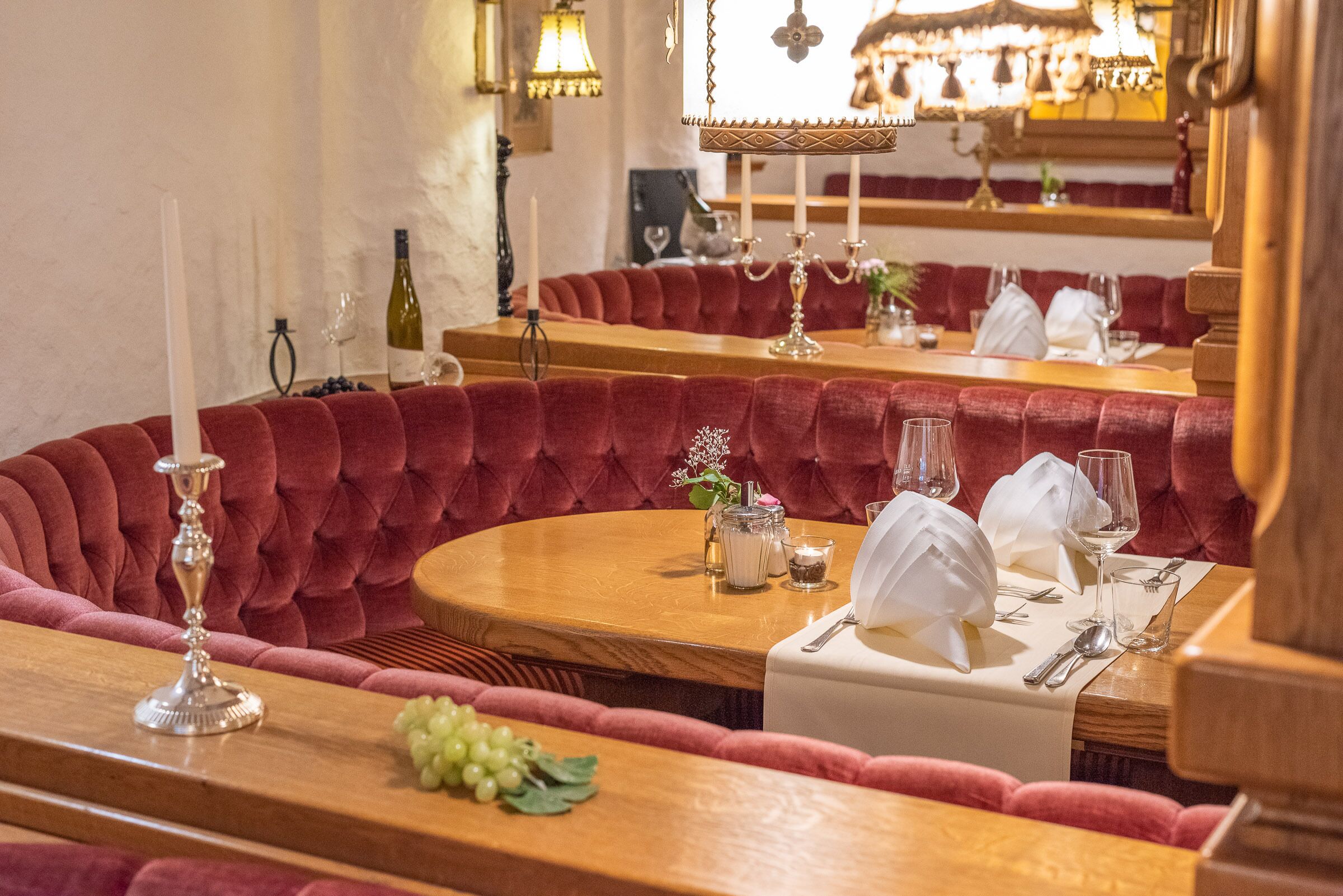 Un restaurante con asientos tapizados en rojo, mesas de madera y manteles blancos.