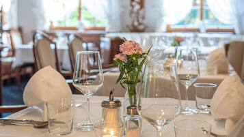 A dining table set with wine glasses, a candle, salt and pepper shakers, and a vase with flowers.