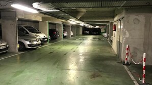 A multi-level parking garage with concrete pillars, green flooring, and white lines marking parking spaces. - Paris15 Balcony Parking, 1bedroom, sleeps 4 (Issy-les-Moulineaux)