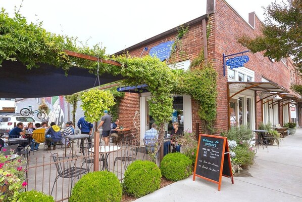 An outdoor café with tables and chairs, a brick building, and a signboard. - Jan Dates Open: Pet friendly near 3 hospitals (Chattanooga)