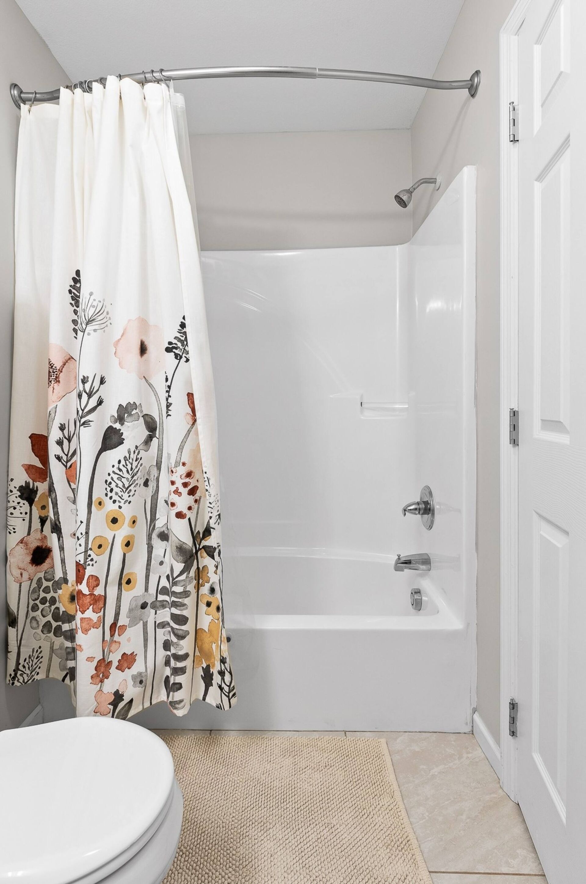 A bathroom with a shower curtain, a bathtub, and a toilet.