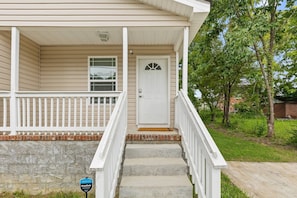A two-story house with a front porch, a white door, and a small front yard. - Jan Dates Open: Pet friendly near 3 hospitals (Chattanooga)