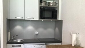 Uma cozinha compacta com lava-louças, micro-ondas e pia.