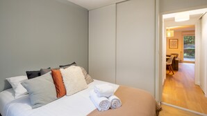 Une chambre d’hôtel avec un lit, des oreillers et une vue sur l’espace extérieur aménagé en coin salon.