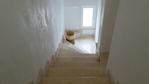 A staircase leading to a room with a window, a door, and a trash can. - Terrazza Primavera by Wonderful Italy (Ostuni)