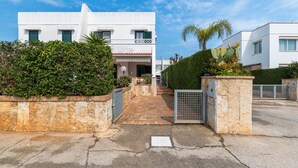 Un edificio moderno con facciata bianca, un balcone e un'area d'ingresso pavimentata.
