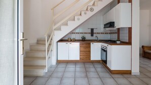 Una cucina con mobili bianchi, un piano di lavoro in legno, un fornello e un lavello.