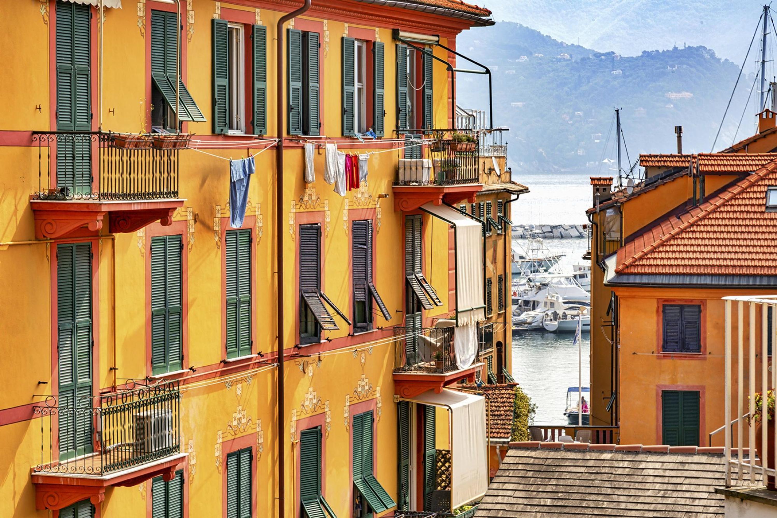 Un immeuble à plusieurs étages doté de balcons, offrant une vue sur la mer et s’inscrivant dans un paysage montagneux.