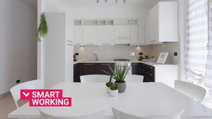 Une cuisine moderne avec des meubles blancs, un îlot central et un coin repas avec des chaises blanches.