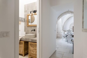 Un baño moderno con un lavabo redondo, armarios de madera y un espejo encima.