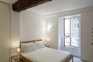 Ein Schlafzimmer mit einem hölzernen Bett, zwei Nachttischlampen, einem Fenster mit Ausblick und einer Wandleuchte.