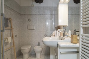 Ein Badezimmer mit Toilette, Bidet und Waschbecken mit Toilettenartikeln.