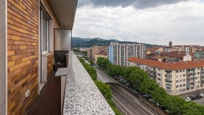 A balcony with a view of a cityscape, including buildings and a road.