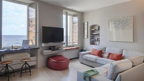 Una sala de estar moderna con un televisor grande, un sofá, una mesa de centro y un sillón de peluche rojo.