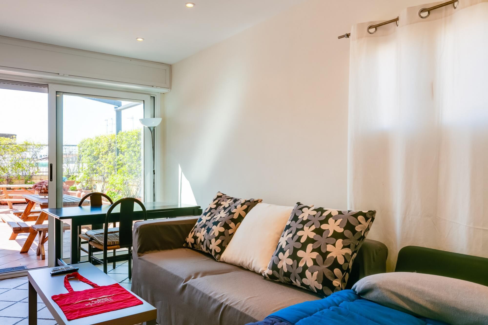 A room with a sofa, a table, and a chair. There is a window with a view of the outside.