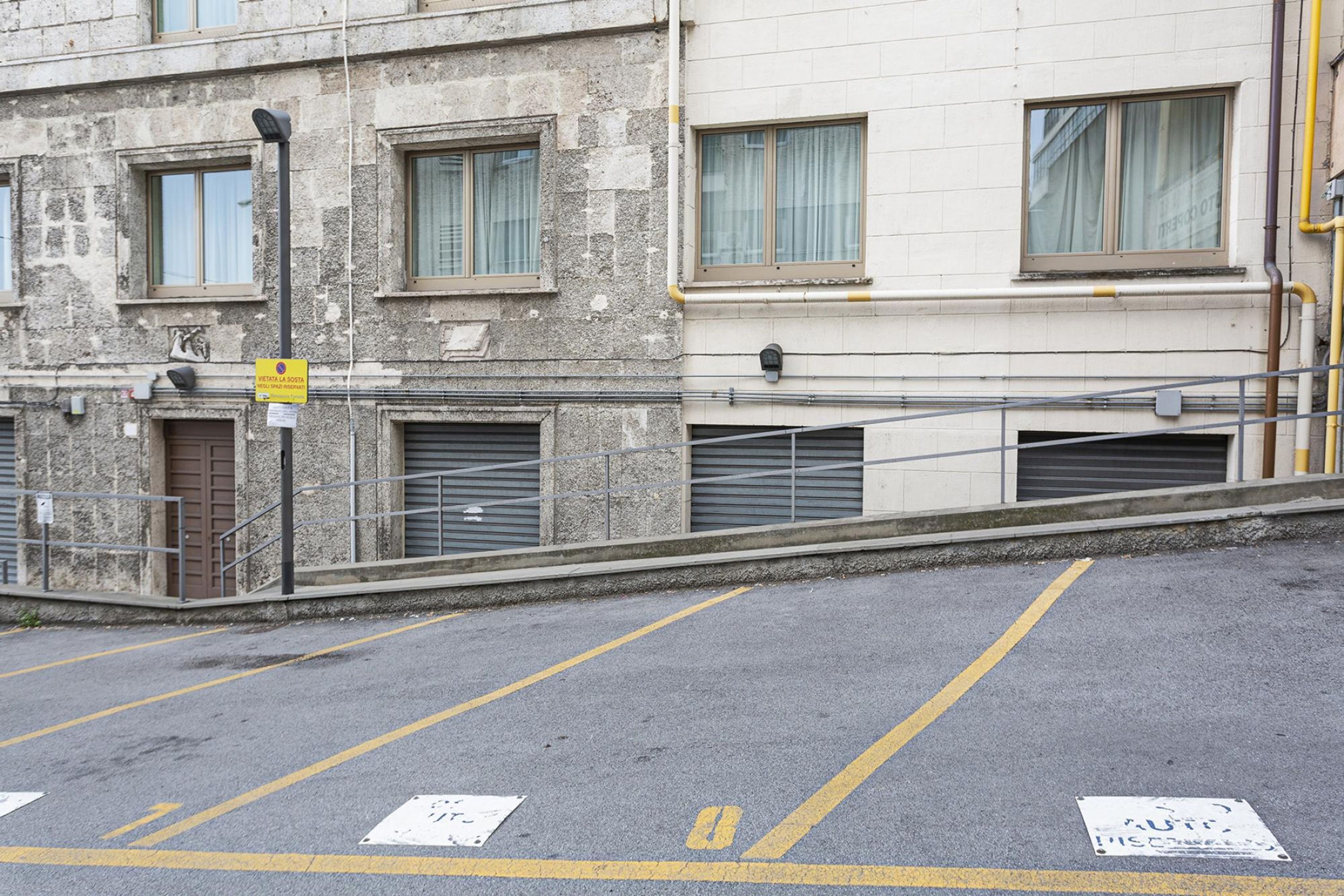 Uma área de estacionamento com linhas amarelas e uma placa indicando zona proibida para estacionar.