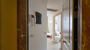 En hotellkorridor med en vägg av marmor, en telefon och en säng i bakgrunden.
