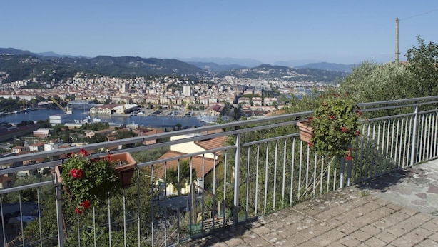 Un paisaje urbano con un río, edificios y montañas al fondo.